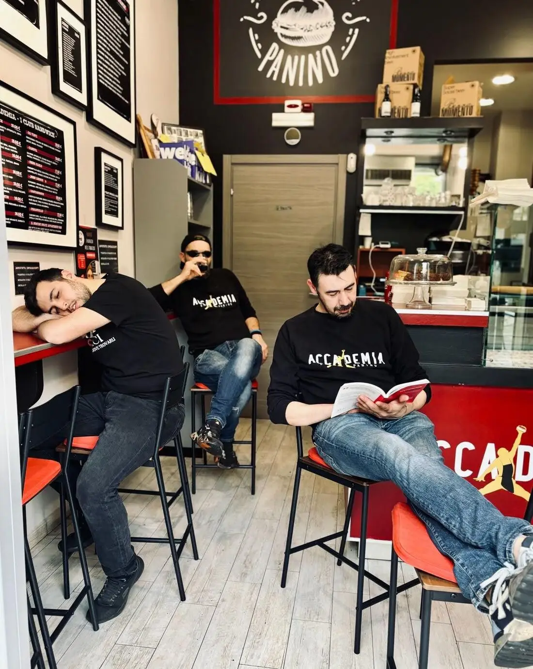 The staff posing in the shop: one studies a book, one sleeps on the counter, one drinks